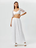 Woman posing with her hand on her hip in a white lace crop top and maxi skirt