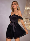 Woman in a black satin and lace A-line dress with off-the-shoulder lace sleeves, styled for an evening event.