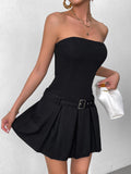 Woman holding a white handbag and posing in a black strapless dress