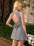 Rear view of a woman in a black and white gingham check sleeveless A-line dress, showcasing the open back with a bow tie closure.