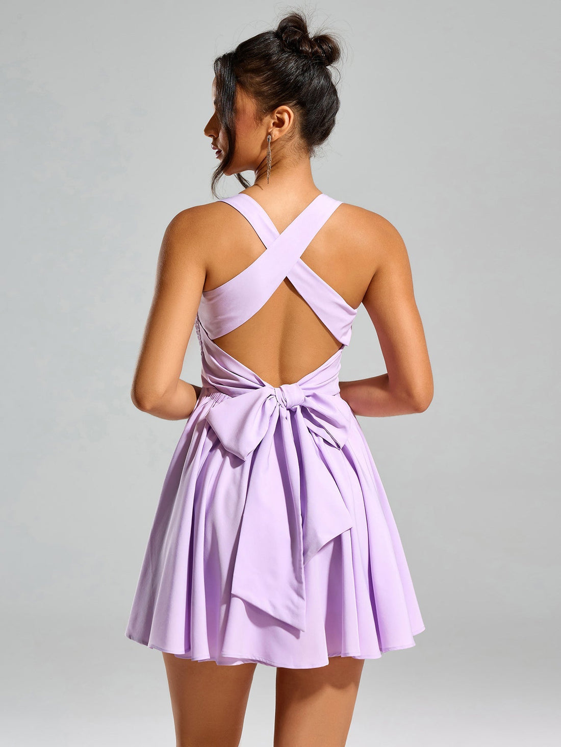 Woman wearing a lavender smocked mini dress with ruffle trim and square neckline