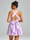Back view of a woman in a lavender smocked mini dress with criss-cross straps and a large bow