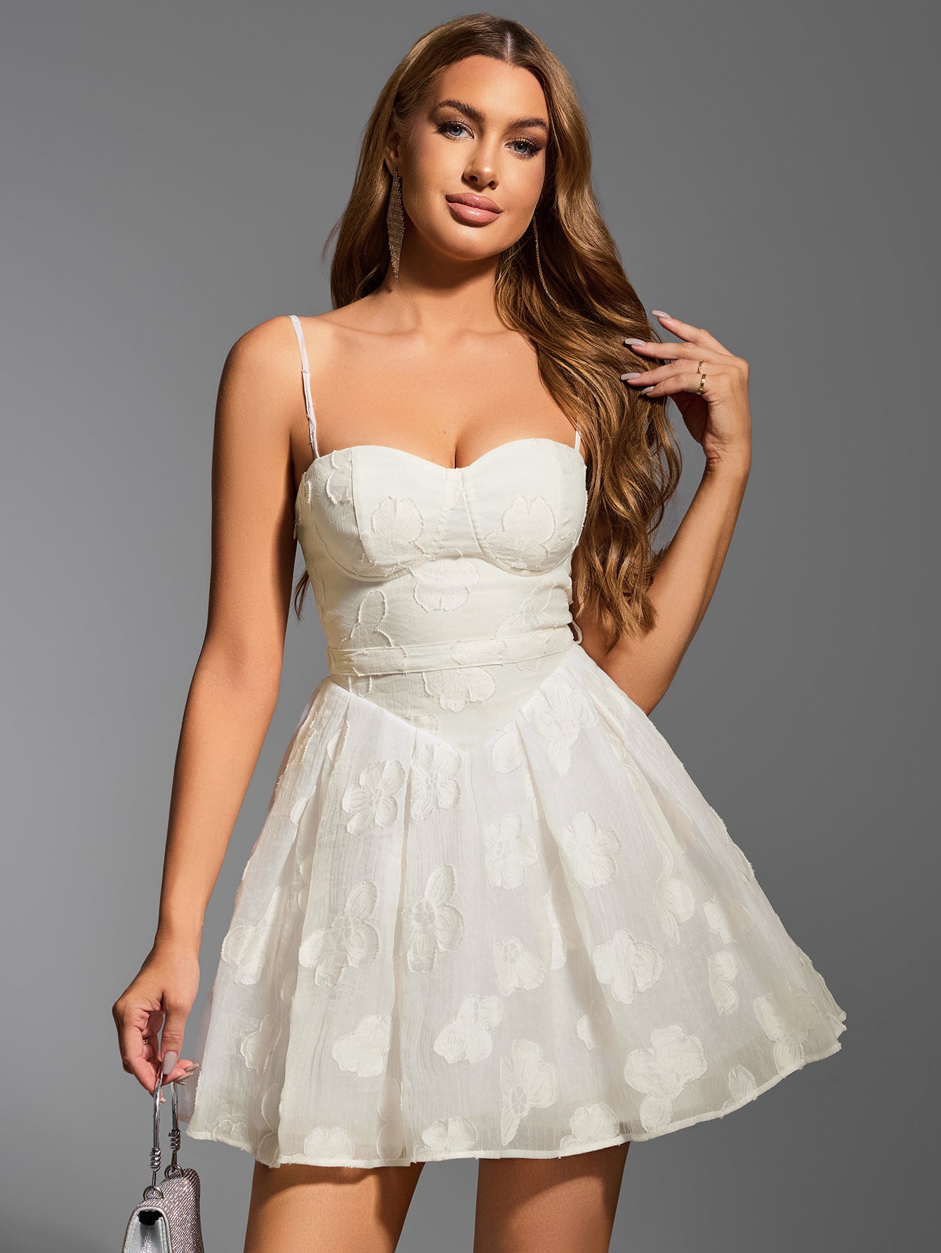 Woman wearing white embroidered floral sweetheart neckline spaghetti strap fit and flare dress holding a handbag