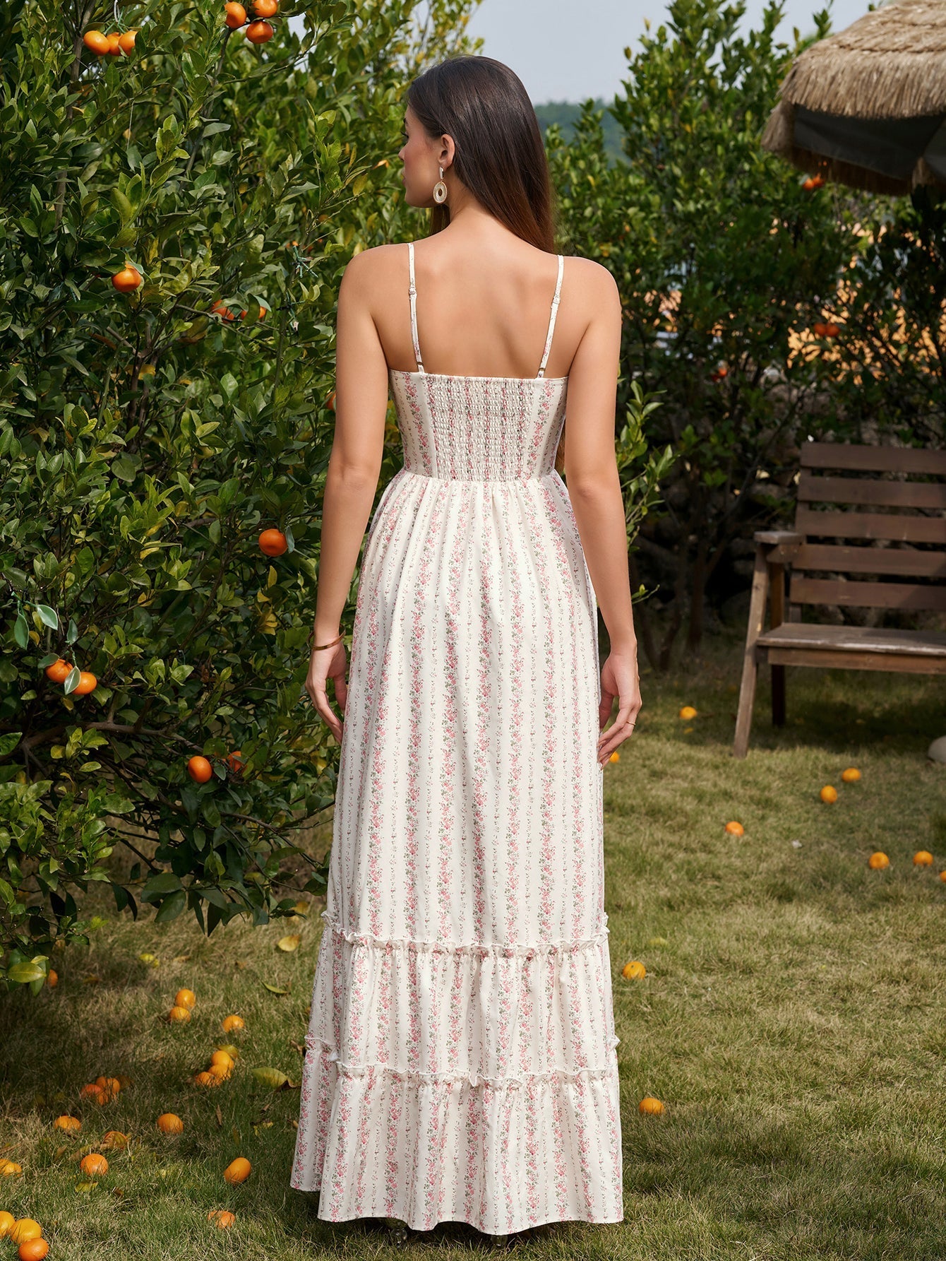 Rear view of a woman in a floral print maxi dress with spaghetti straps and a tiered hem.