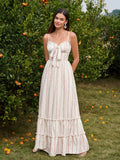 Woman wearing a floral print maxi dress with spaghetti straps and a tie-front bodice standing in an orchard.