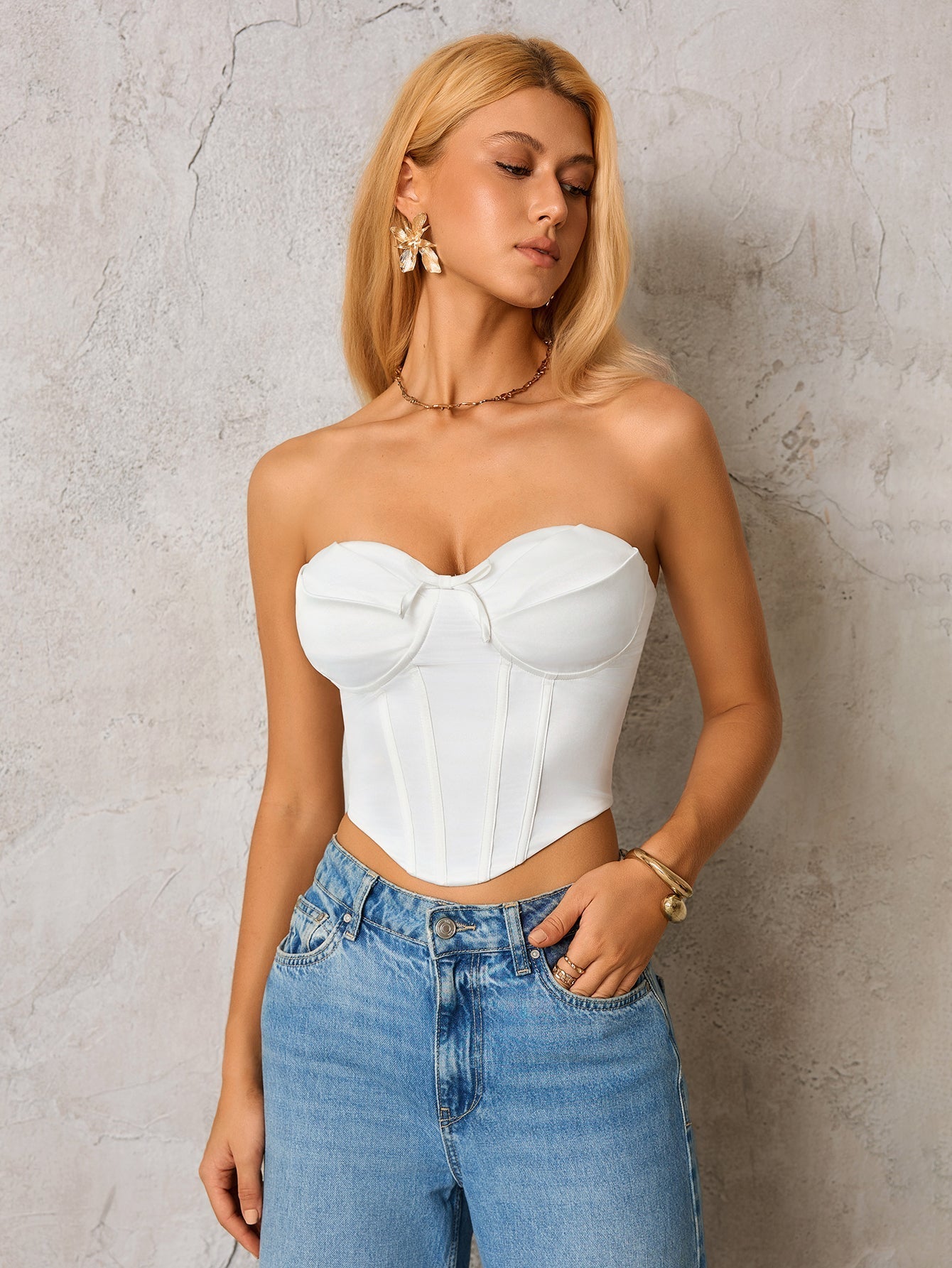 Woman wearing a white strapless corset top and blue denim jeans, front view