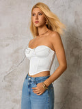 Woman wearing a white strapless corset top and blue denim jeans, side profile