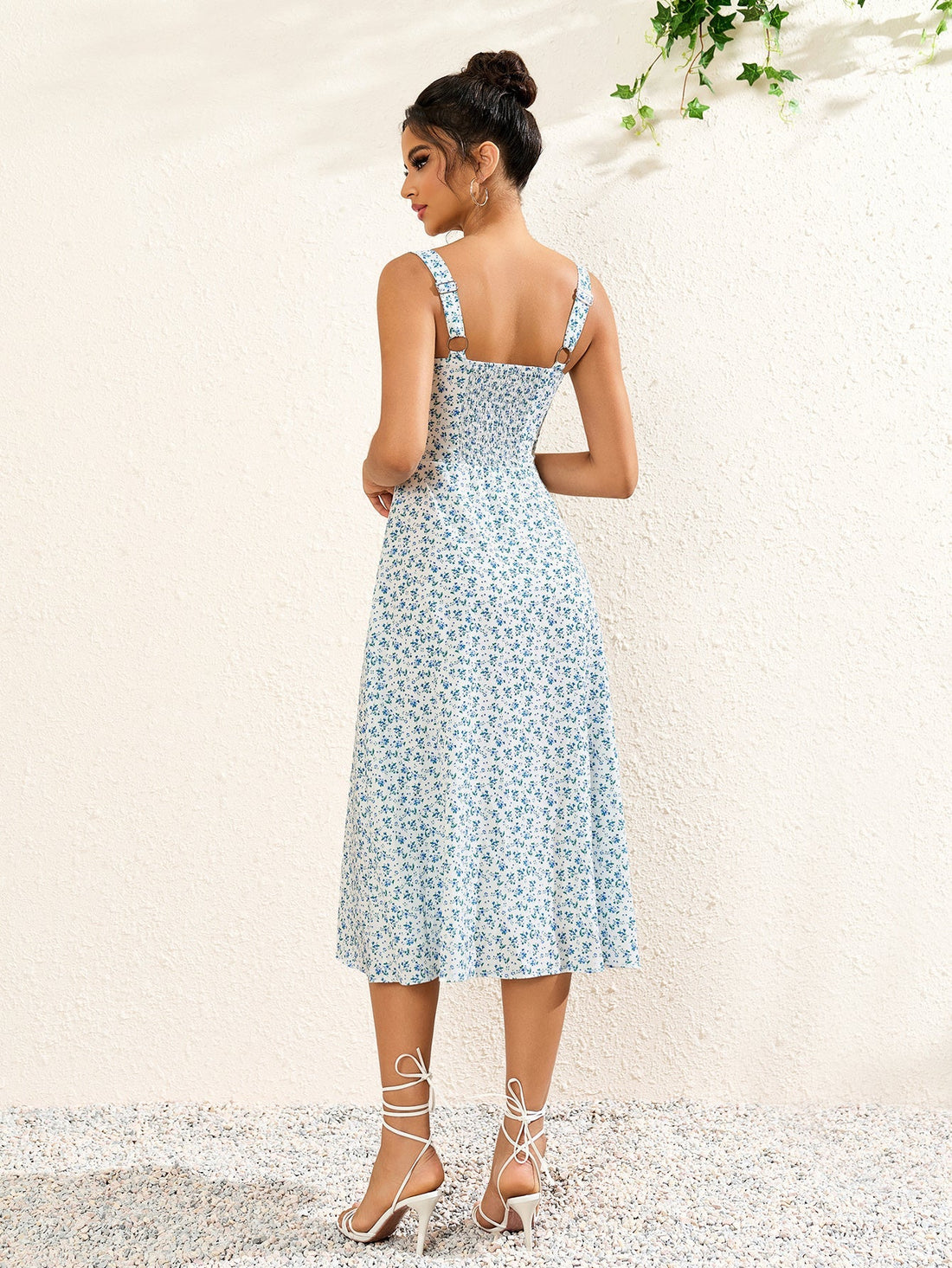 Woman wearing a white midi dress with a blue floral print, square neckline, and tie detail.