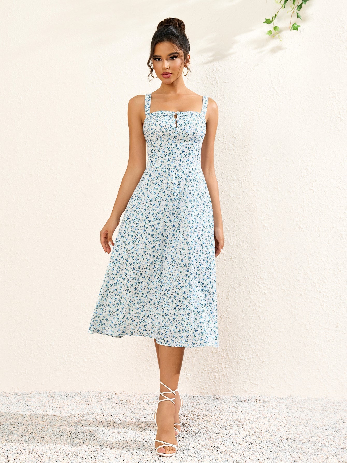 Front view of a woman in a white floral print midi dress with spaghetti straps and a flared skirt.