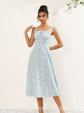 Woman wearing a white midi dress with a blue floral print, square neckline, and tie detail.