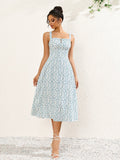 Full length shot of a woman posing in a white and blue floral print midi dress with a square neckline.