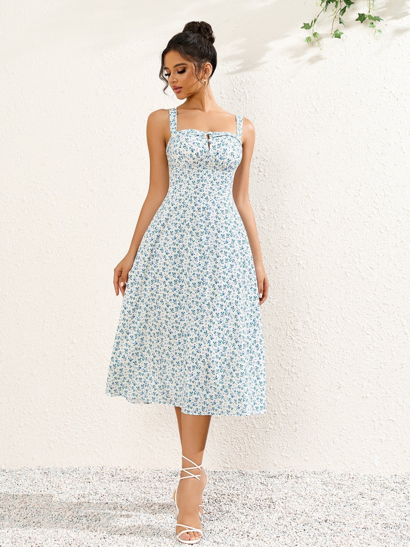 Full length shot of a woman posing in a white and blue floral print midi dress with a square neckline.