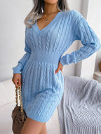 Model holding a handbag with a blue cable knit sweater dress