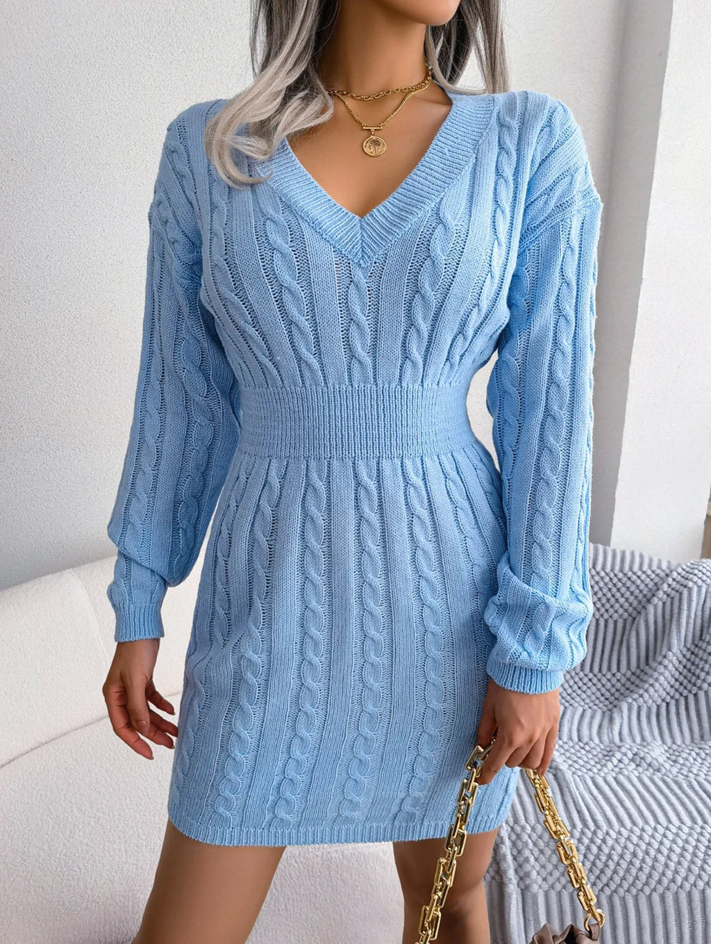 Model posing in a blue cable knit sweater dress