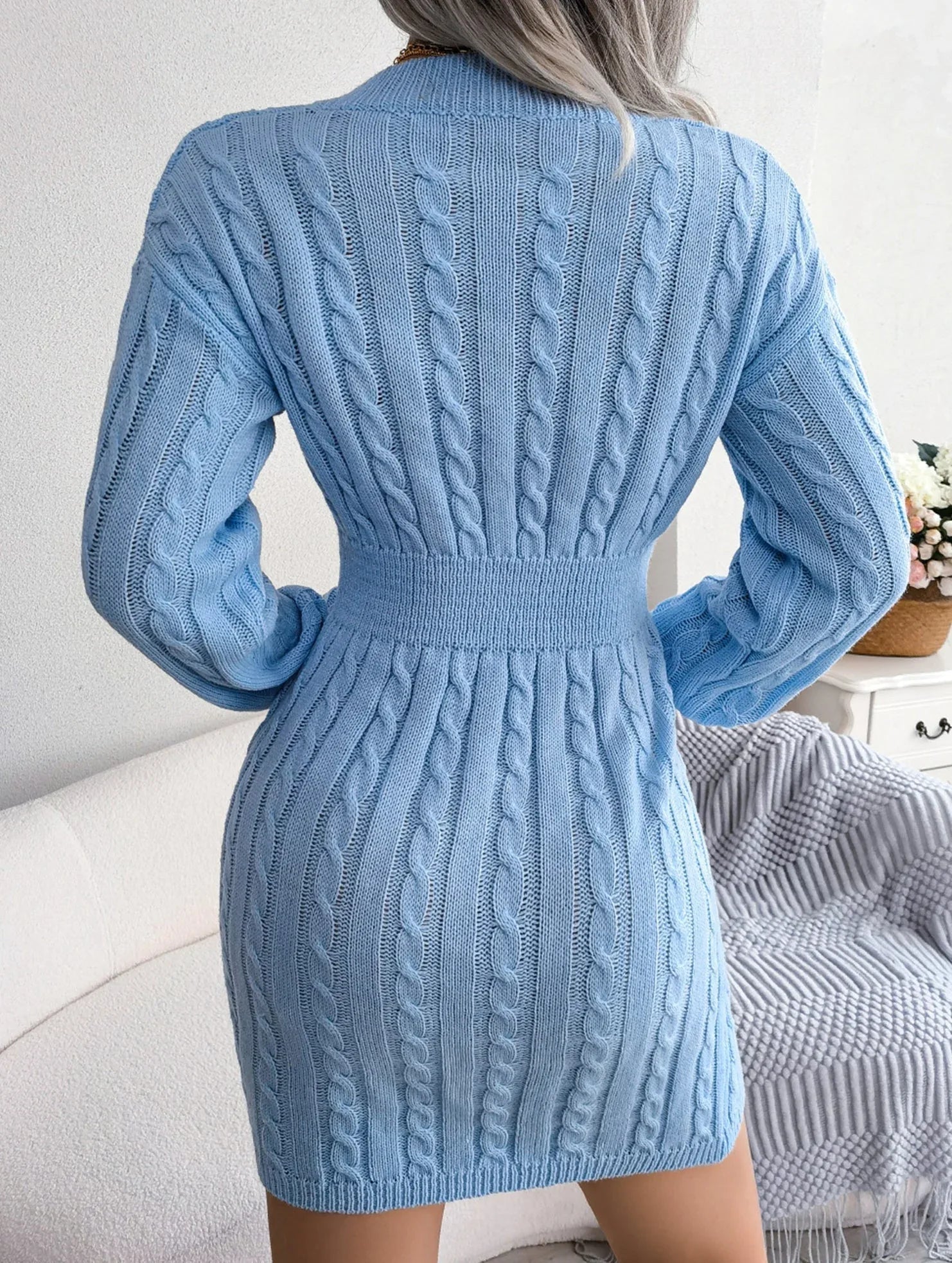 Back view of a blue cable knit sweater dress with a fitted waistband