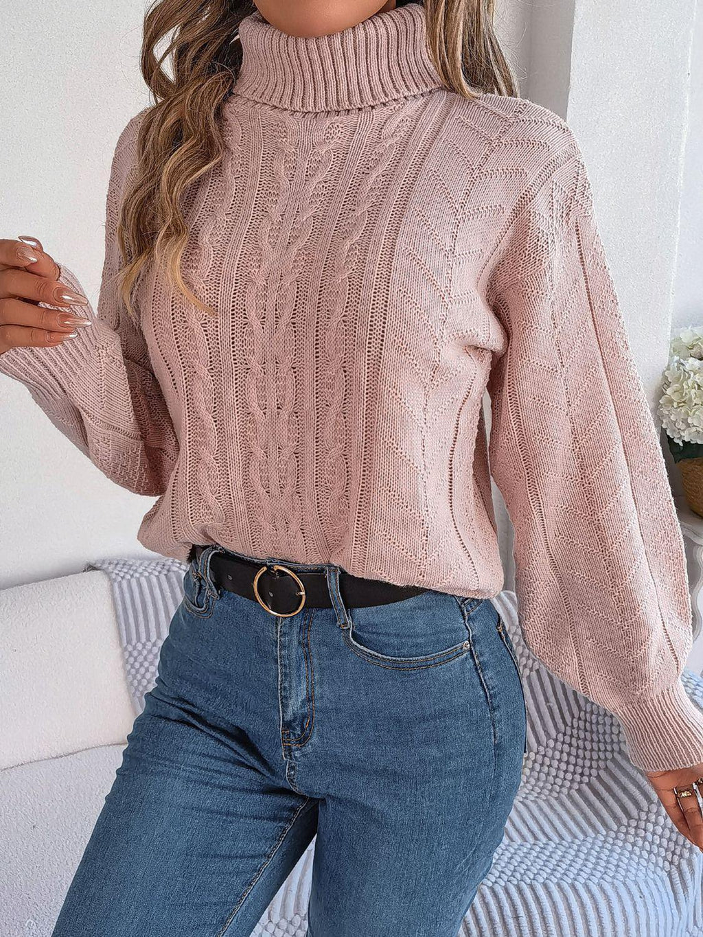 Close-up of a woman in a pink cable knit turtleneck sweater and blue jeans