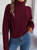 Woman wearing a burgundy cable knit turtleneck sweater with blue jeans