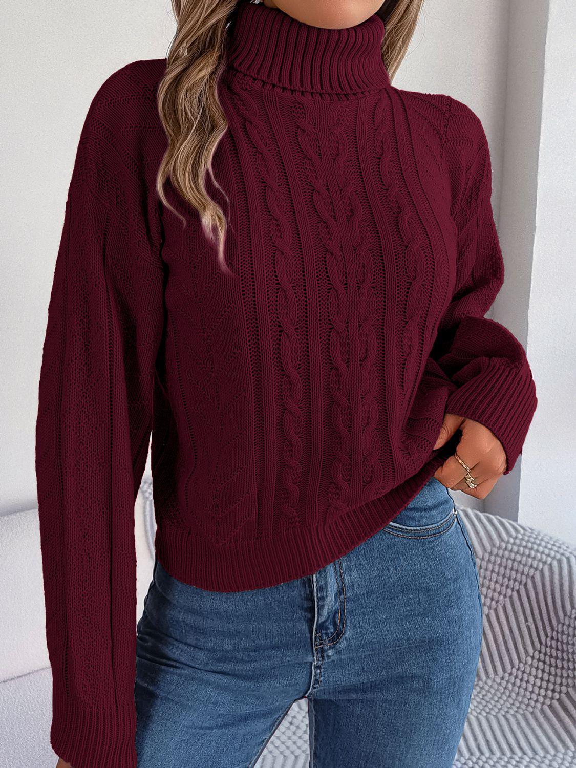 Woman wearing a burgundy cable knit turtleneck sweater with blue jeans