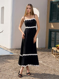 Woman wearing a black midi dress with white scalloped trim and spaghetti straps.