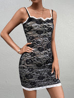 Woman posing in a black lace sheath dress with white trim and spaghetti straps.