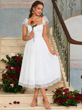Woman in a black satin fit and flare midi dress with spaghetti straps and white lace trim, holding a silver clutch.