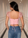 Back view of a woman in a pink corset back crop top and blue jeans