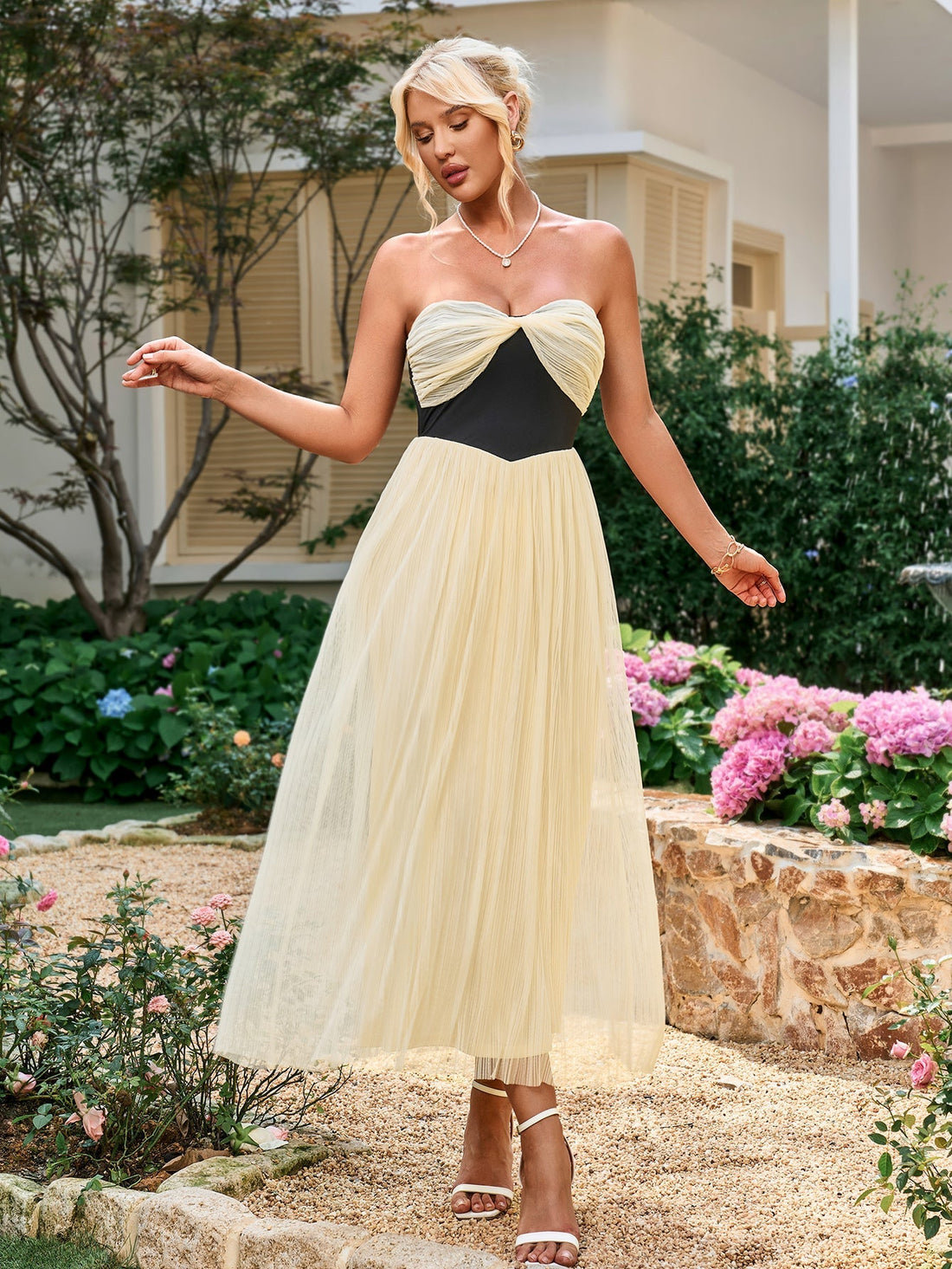Woman wearing a pink strapless tulle dress with a ruched bodice and A-line skirt.