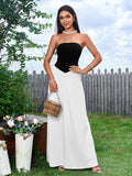 Woman in a black and white strapless maxi dress holding a woven handbag