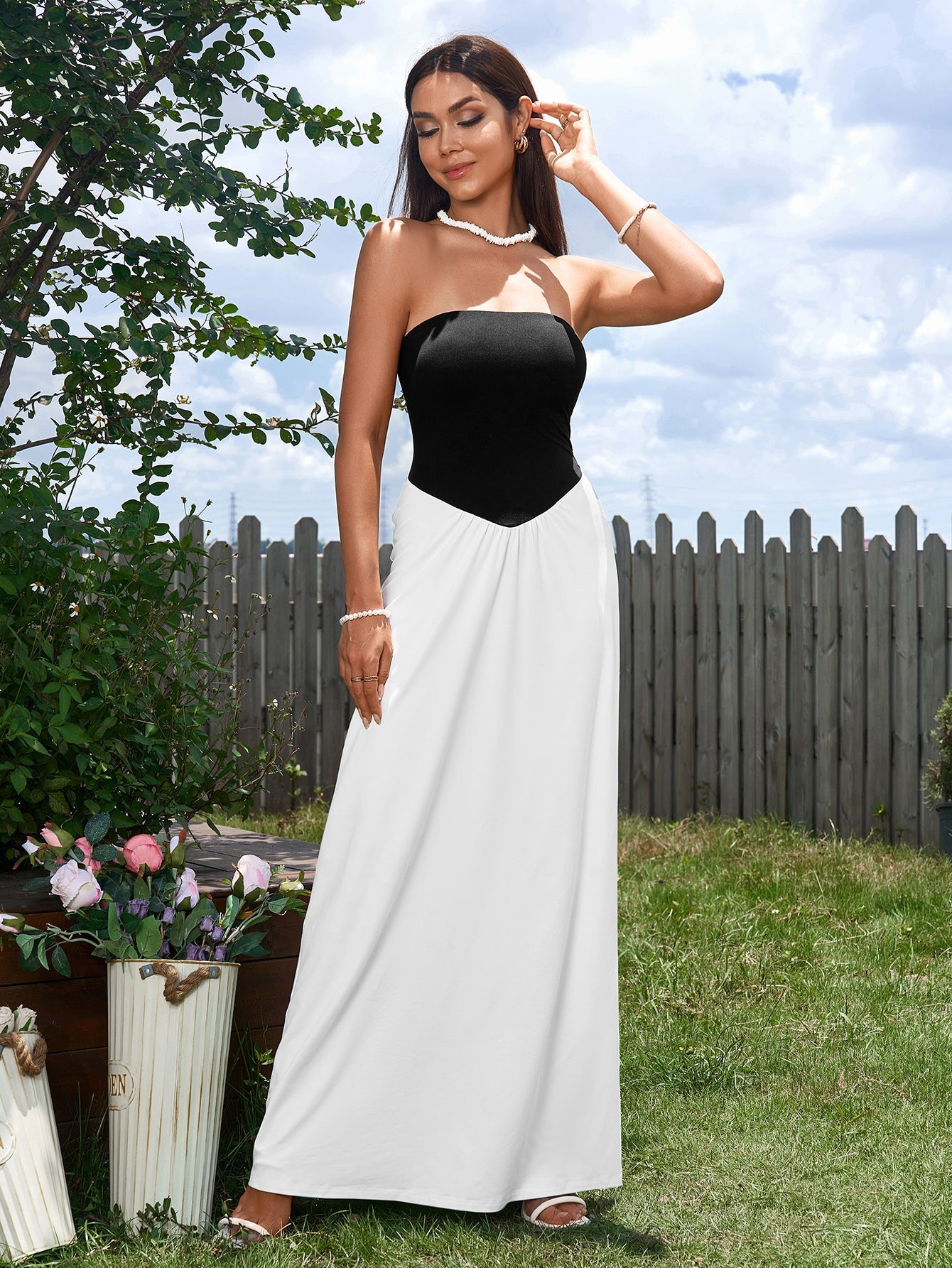 Woman in a black and white strapless maxi dress adjusting her sunglasses