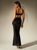 Back view of a woman in a black column gown with a backless design and sequined skirt.