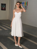Full body shot of a white midi dress with a gathered waist