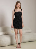 Woman modeling a black floral jacquard sheath dress with spaghetti straps and a square neckline, holding a pearl handbag.