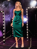 Front view of a woman in a green satin sheath dress with strappy sweetheart neckline.