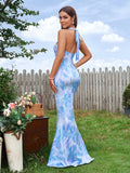 Rear view of a woman in a blue and white abstract print mermaid gown, showing the halter tie detail.