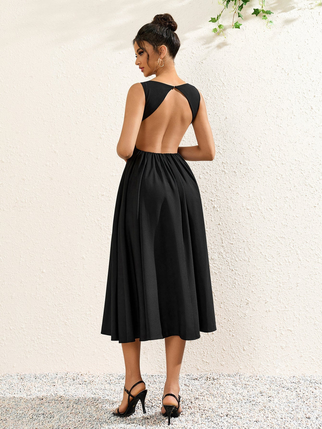woman wearing a sleeveless black crepe midi dress with a boat neckline and flared skirt