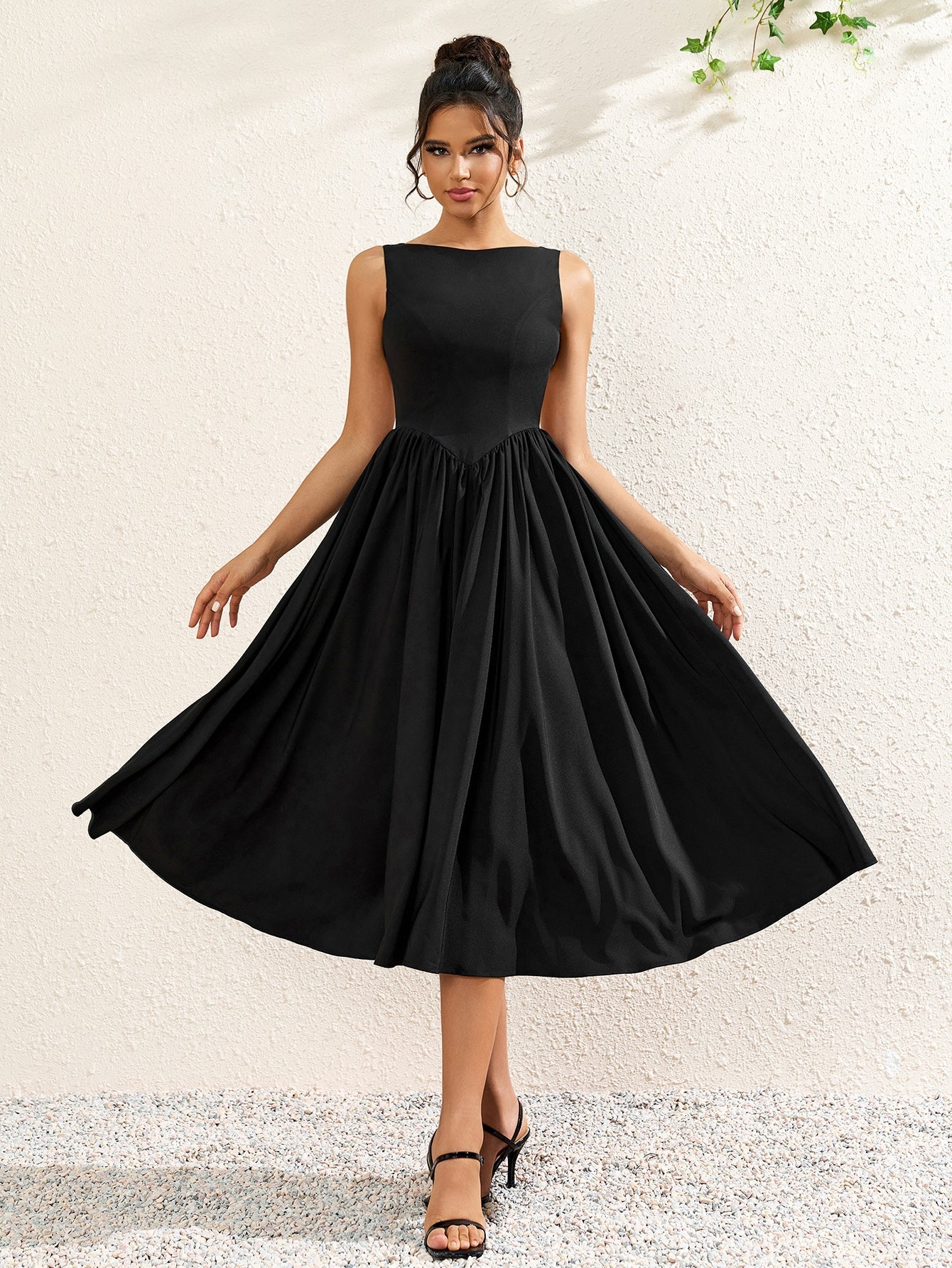woman wearing a sleeveless black crepe midi dress with a boat neckline and flared skirt