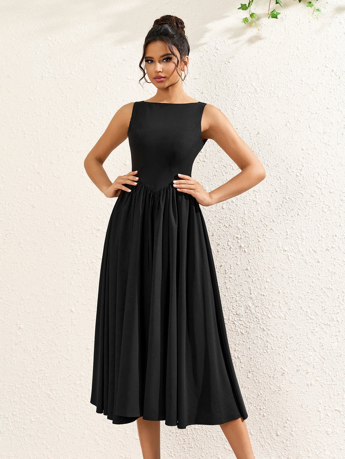 woman posing in a sleeveless black crepe midi dress with a boat neckline and flared hem