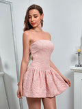 Woman in a pink strapless jacquard mini dress, looking down.