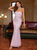 Fashionable woman posing in a long pink sequined mermaid dress with elegant draping.