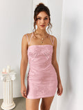 Woman wearing a pink floral jacquard sheath dress with a square neckline and spaghetti straps, styled with layered necklaces.