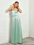 Woman adjusting her earrings while wearing a mint green satin maxi dress.