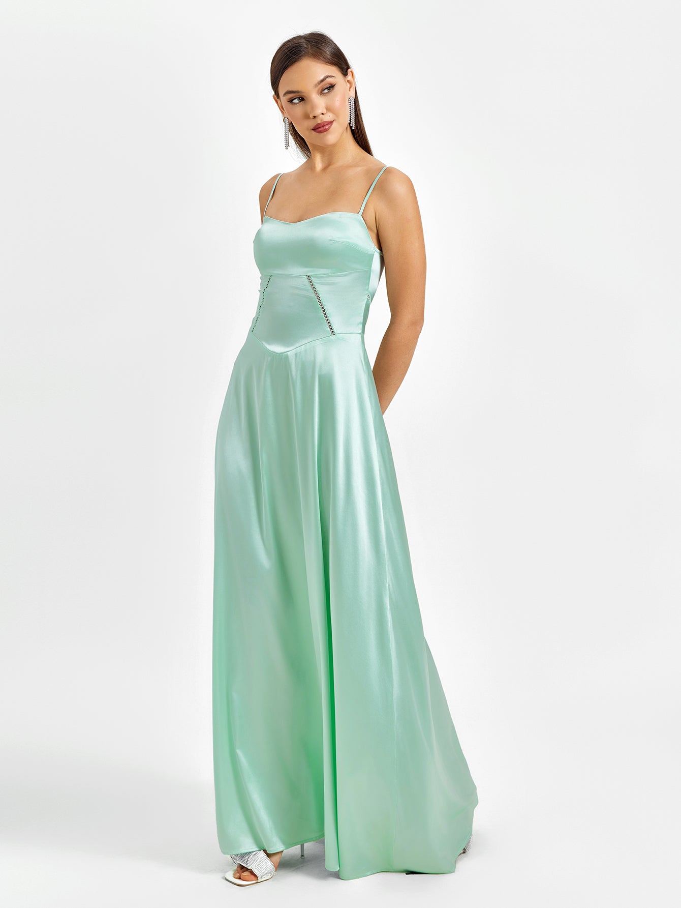 Woman with hands behind her back in a mint green satin maxi dress.