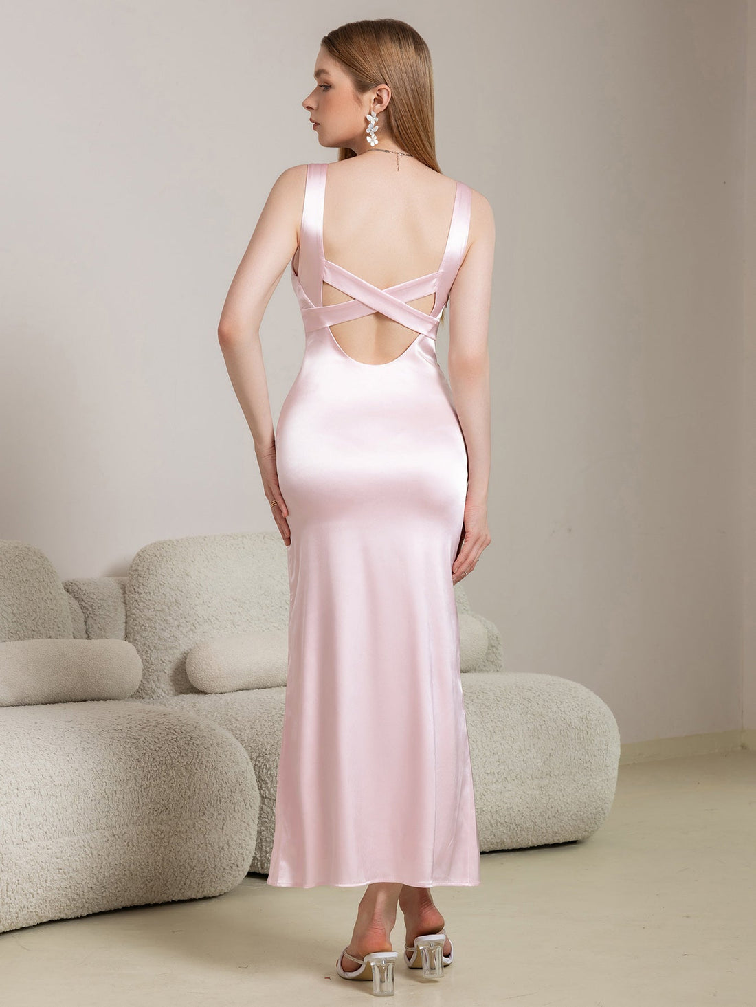 Woman wearing a pink satin maxi dress with a square neckline and spaghetti straps.