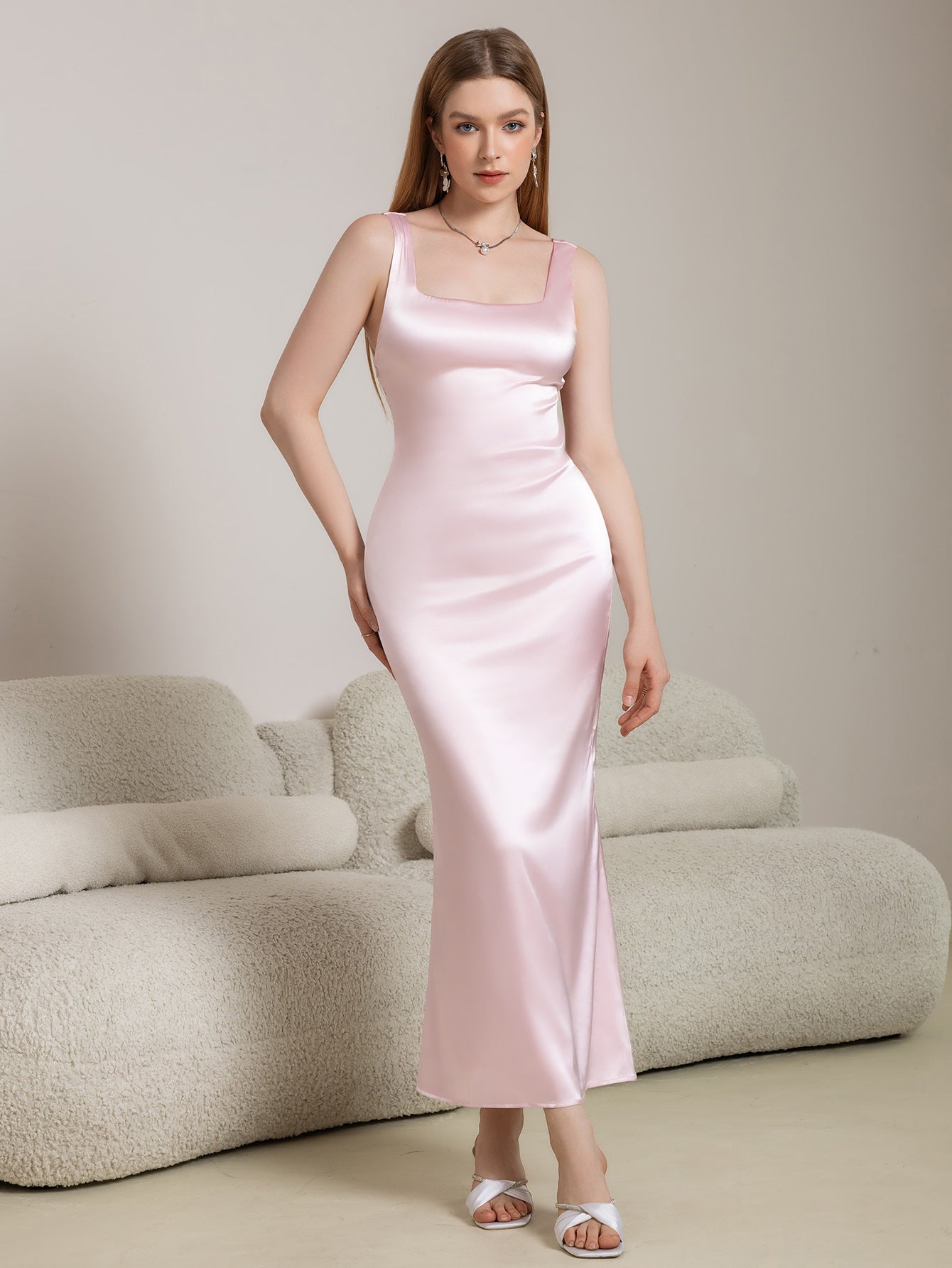 Woman wearing a pink satin maxi dress with a square neckline and spaghetti straps.