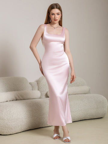 Woman wearing a pink satin maxi dress with a square neckline and spaghetti straps.