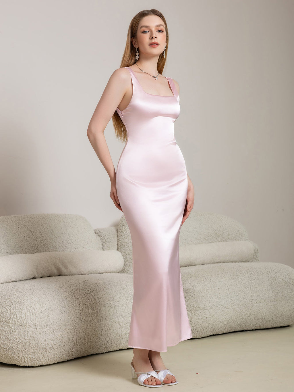 Full-length view of a woman in a pink satin column dress with a square neckline.