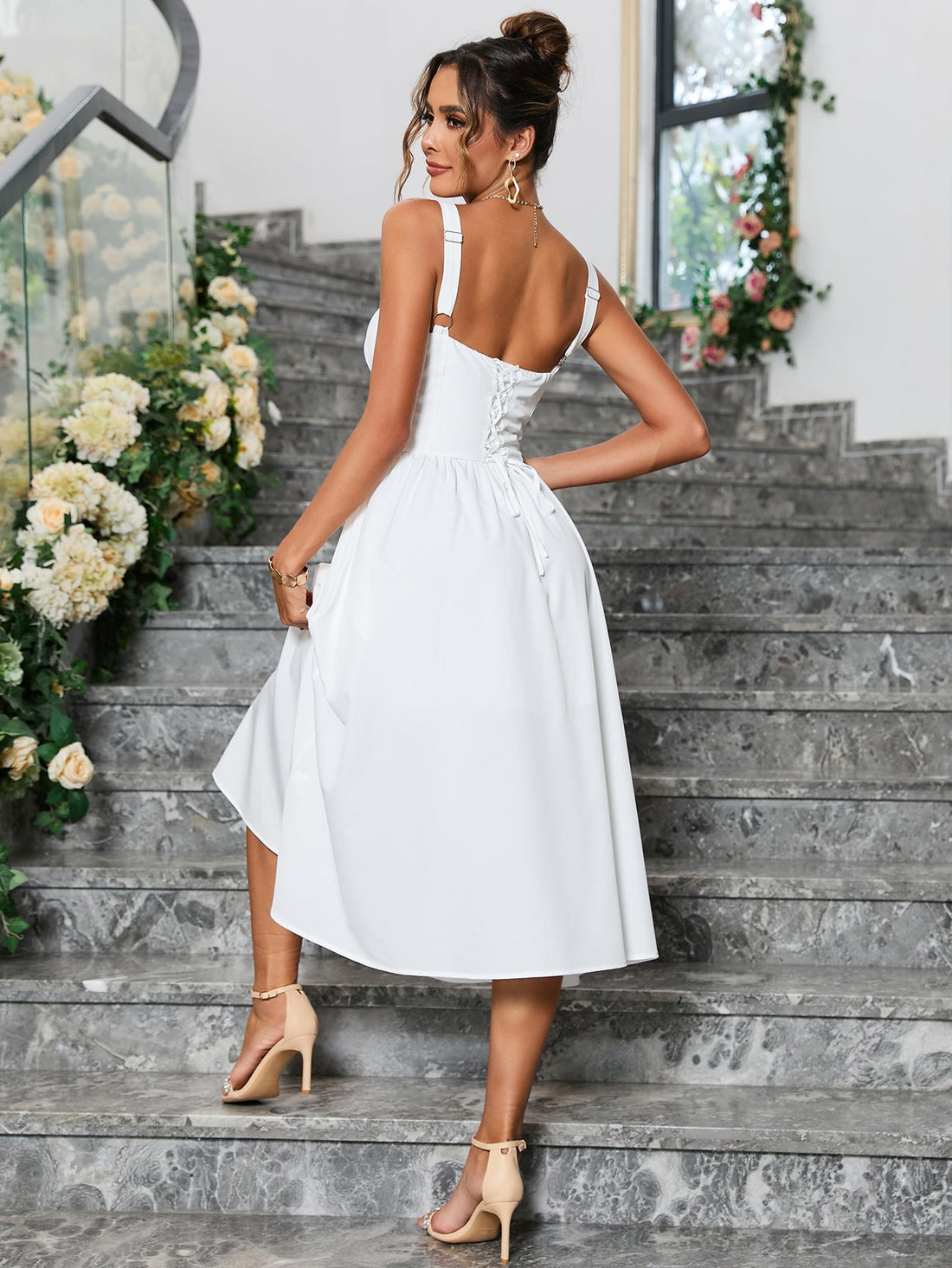 Woman wearing a white sleeveless midi dress with a sweetheart neckline and button front detail, standing on stairs.