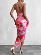 Woman wearing a pink floral print ruched bodycon midi dress with spaghetti straps and a side slit, viewed from the front.