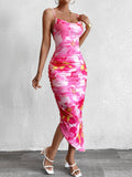 Woman wearing a pink floral print ruched bodycon midi dress with spaghetti straps, side slit, and a white handbag.