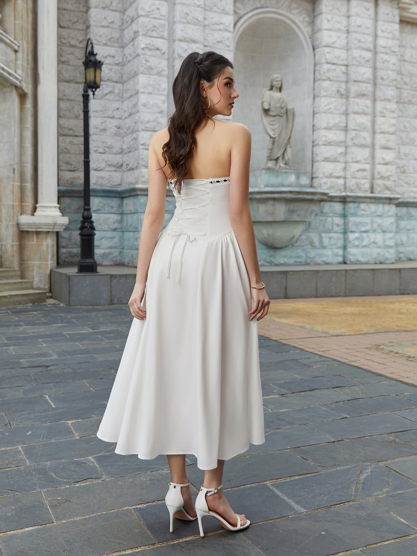 Back view of a woman in a white strapless midi dress with corset lacing